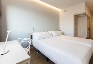 a bedroom with a large white bed and a desk at B&B HOTEL Barcelona Viladecans in Viladecáns