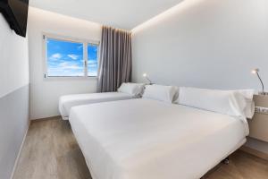 a hotel room with two beds and a window at B&B HOTEL Barcelona Viladecans in Viladecáns