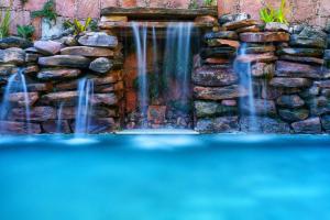 a waterfall in a stone wall with a pool of water at Pousada Vila Serrano in Lençóis