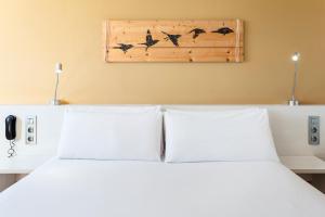a bedroom with a white bed with birds on the wall at B&B HOTEL Barcelona Viladecans in Viladecáns