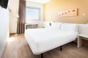 a hotel room with a white bed and a window at B&B HOTEL Barcelona Viladecans in Viladecáns