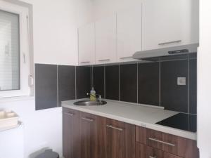 uma cozinha com armários brancos e um lavatório em Apartmani Nana Sokobanja em Sokobanja