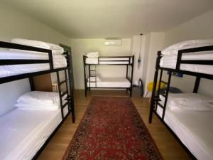 a room with three bunk beds and a rug at Vanilla Sky Boutique Hostel in Tirana