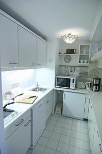 eine weiße Küche mit einer Spüle und einer Mikrowelle in der Unterkunft Apartment Di Wiis in Westerland
