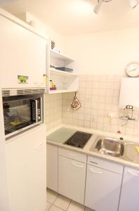 uma cozinha branca com um lavatório e um micro-ondas em Ferienwohnung Austernfischerin em Westerland