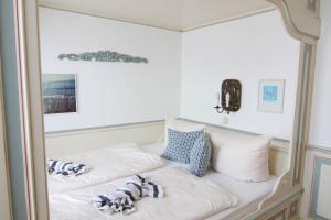 een wit bed met kussens in een kamer bij Ferienwohnung Kleine Düne in Westerland