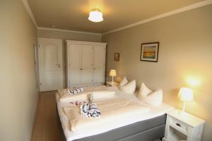 - une chambre avec un grand lit blanc et 2 oreillers dans l'établissement Eidumhüs, à Westerland