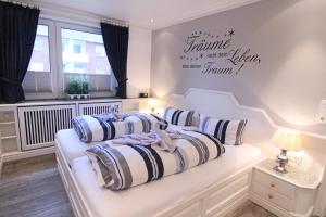 Dormitorio blanco con cama con almohadas en Käpt`n Hörnchen, en Hörnum