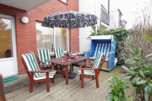 une table et des chaises avec un parasol sur une terrasse dans l'établissement Haus Heidi, à Westerland