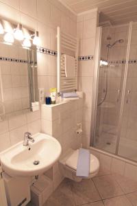 une salle de bain avec un lavabo, des toilettes et une douche dans l'établissement Haus Heidi, à Westerland