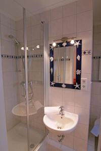 une salle de bain avec un lavabo et une douche avec un miroir dans l'établissement Haus Heidi, à Westerland 11 autres photos