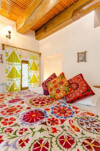 una cama con almohadas coloridas en una habitación en Amulet Hotel, en Bukhara