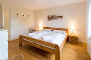 ein Schlafzimmer mit einem großen Holzbett mit weißer Bettwäsche in der Unterkunft Haus Seeblick II in Glücksburg