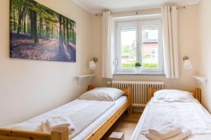 two beds in a room with two windows at Ferienhaus Seeblick - gemütliche 60qm - 50m zum Naturstrand - mit Terrasse und großem Garten in Glücksburg