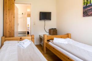 two beds in a room with a tv on the wall at Ferienhaus Seeblick - gemütliche 60qm - 50m zum Naturstrand - mit Terrasse und großem Garten in Glücksburg