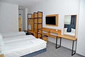 ein Zimmer mit zwei Betten, einem Schreibtisch und einem Fernseher in der Unterkunft Hotel Ricas in Sliven