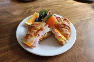 a white plate with croissants and fruit on a table at Les Petits Trésors in Coaticook