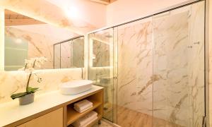 uma casa de banho com uma cabina de duche em vidro e um lavatório. em Pal Calma Suites em Rethymno Town
