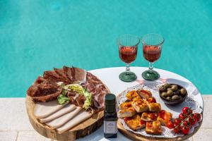 uma mesa com um prato de comida e dois copos de vinho em Relais Trulli Le Icone em Ostuni
