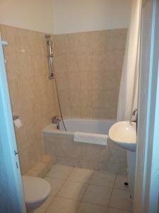 a bathroom with a tub and a toilet and a sink at Hôtel Etang des Reynats in Chancelade