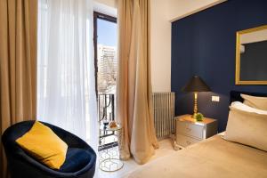 a bedroom with a bed and a chair and a window at Metropole Apartments Studio Old City in Bucharest