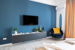 salon z telewizorem na niebieskiej ścianie w obiekcie Metropole Apartments Studio Old City w Bukareszcie