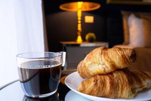 a plate with two croissants and a glass of soda at Metropole Apartments Studio Old City in Bucharest