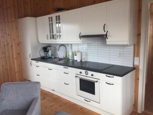 a kitchen with white cabinets and a black counter top at Riisebruket in Havningberg