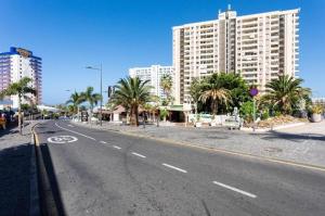 una strada vuota con palme e un edificio alto di Playa Paraíso PARKING Y WIFI FREE!!!!! a Playa Paraiso