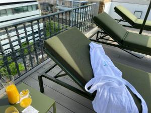 a chair and a table on a balcony with orange juice at Aquitania Home Suites in Seville