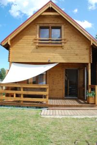 a log house with a porch and a white awning at Omega Niechorze Domki Letniskowe in Niechorze