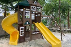 ein Spielplatz mit Rutsche und Spielhaus in der Unterkunft La Casa del Arbol -4bed 3 bath in Puerto Morelos