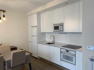 a kitchen with white cabinets and a sink and a microwave at Casa Cotefablo. Alojamiento Ara (Gavin, Biescas) in Gavín