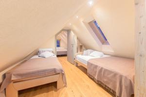 a attic bedroom with two beds and a window at Bohinj Cottage Pr' Maricki - house in nature with hot tub & sauna in Bohinj