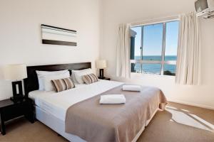 
a hotel room with a bed, chair and a window at The Point Resort in Bargara
