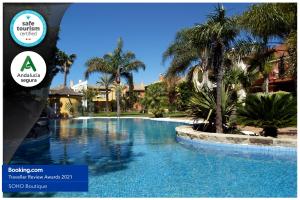 una piscina en un complejo con palmeras en Apartamentos Soho Boutique Vistahermosa, en El Puerto de Santa María