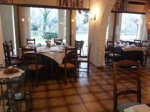 een eetkamer met tafels, stoelen en ramen bij Hôtel Etang des Reynats in Chancelade