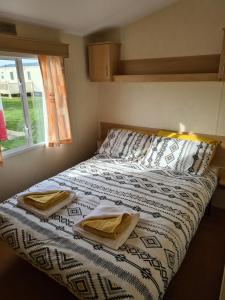 Una cama en un dormitorio con dos toallas. en Golden Palm - Meadow Lakes, en Chapel St. Leonards