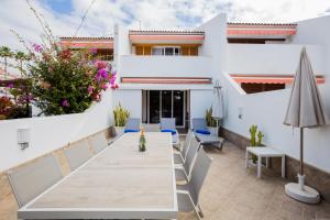 un patio con tavolo e sedie e un edificio di GO2TENERIFE Tropicana Villa Santiago 2 a Playa de las Americas