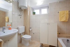 a white bathroom with a toilet and a sink at Apartman Vite in Podgora