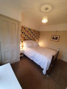 a bedroom with a large white bed and a lamp at The Lodge Stanwell in Stanwell