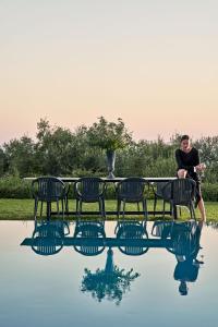 VirósにあるThe Designer's Villa - Member of Spiritual Living Corfuの水のプールの横のベンチに座っている女性
