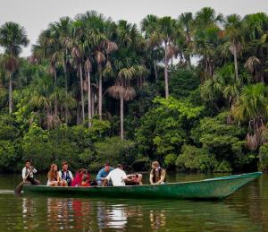 a group of people in a green boat on the water at Monte Amazonico Lodge in Tambopata