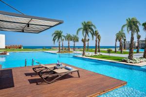 a pool with a picnic table on a wooden deck at Rixos Premium Magawish Suites and Villas- Ultra All-Inclusive in Hurghada