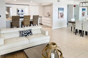 Daytona Beach Soaring في Daytona Beach Shores: غرفة معيشة مع أريكة بيضاء ومطبخ