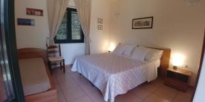 sypialnia z łóżkiem, krzesłem i oknem w obiekcie La Piana degli Ulivi w mieście Rossano