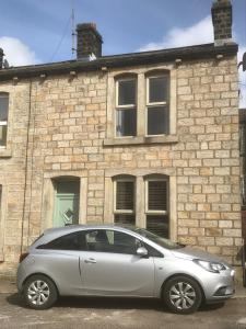 a silver car parked in front of a brick building at Woodland Cottage in Cowling