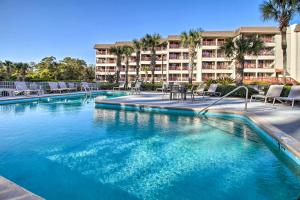 a swimming pool with chairs and a hotel in the background at Steps to Beach Ocean-View Hilton Head Villa! in Hilton Head Island