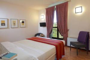 ein Schlafzimmer mit einem Bett, einem Fenster und einem Stuhl in der Unterkunft Locanda dell'Arte in Solonghello