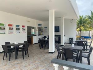 Un comedor con mesas y sillas negras. en Hotel Villa del Mar Coveñas, en Coveñas